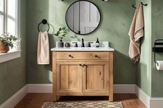 a bathroom with green walls and white fixtures, including a wooden sink vanity topped with a round mirror