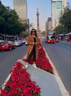 a woman standing in the middle of a street with poinsettias on both sides