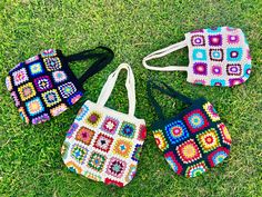 three crocheted purses sitting on the grass with one bag in front of them