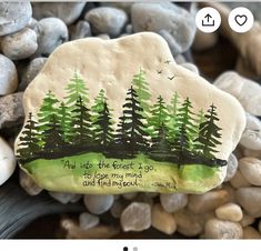 a rock with trees painted on it sitting next to rocks and stones that read, you up into the forest i go to lose my mind and find peace