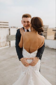 a bride and groom embracing each other on top of a roof