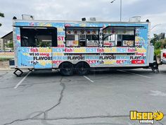 a food truck parked in a parking lot next to other vehicles and people standing around