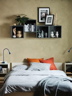 a bed with white sheets and pillows in front of two bookshelves on the wall