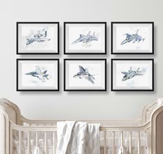 four framed photographs of fighter jets hang on the wall above a crib in a nursery