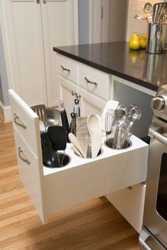 an open drawer in the middle of a kitchen with utensils and other items