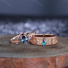 two wedding rings with blue topazte and diamond accents on a tree stump in front of sparkling lights