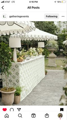 an outdoor bar with white umbrellas and potted plants on the counter in front of it