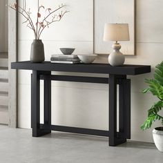 a black table with two vases and a lamp on it next to a potted plant