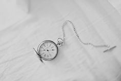 an old pocket watch sitting on top of a white sheet with a chain around it