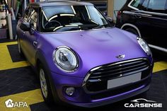 a purple mini car parked in a garage next to another black and white one behind it