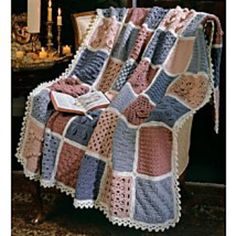 a crocheted afghan is sitting on a chair in front of a fireplace with a book