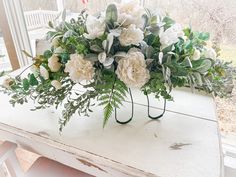 a bouquet of white flowers sitting on top of a wooden table next to a window