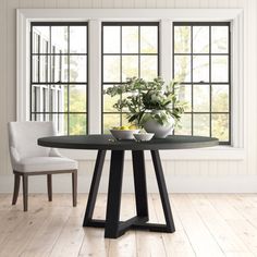 a dining room table with two chairs and a vase on the table next to it