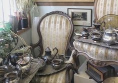 an old fashioned chair and table in a room with potted plants on the side