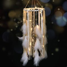 a chandelier with white feathers hanging from it's sides on a black background