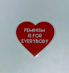 a red heart shaped sticker with the words feminist is for everybody