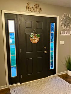 a black front door with the words hello on it and a welcome mat in front