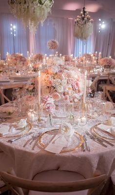 an elegant wedding reception set up with white and pink flowers, candles and centerpieces