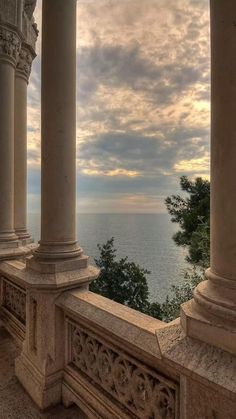 the view from an old building looking out at the water and clouds in the sky