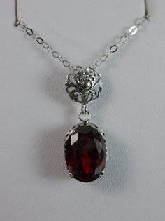 garnet pendant, with a deep red oval stone set in floral sterling silver filigree, 4 prongs hold the gem in place Classic Ruby Filigree Jewelry, Formal Oval Garnet Pendant Jewelry, Elegant Red Engraved Jewelry, Elegant Engraved Red Jewelry, Oval Garnet Filigree Jewelry, Classic Garnet Necklace For Formal Occasions, Elegant Silver Garnet Necklace, Filigree Cubic Zirconia Necklace Gift, Filigree Cubic Zirconia Necklaces As Gifts