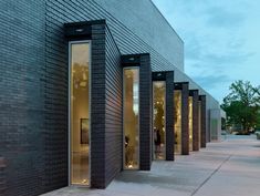 a row of windows on the side of a black brick building with people walking by