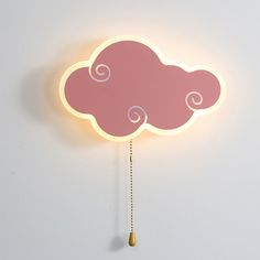 a pink cloud shaped clock hanging from the side of a wall next to a chain