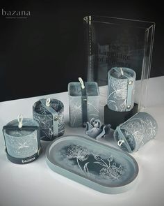 an assortment of glass items are displayed on a white table top with black and silver accents