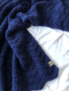 a blue knitted blanket laying on top of a bed