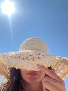 a woman wearing a large straw hat on top of her head with the sun shining in the background