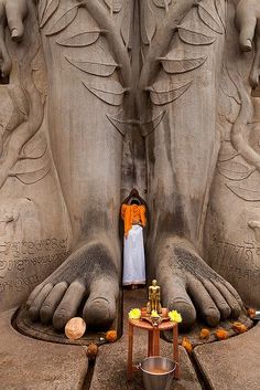 a person sitting in front of a large statue