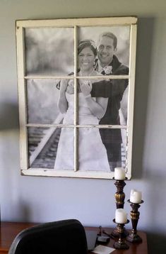 an old window is hung on the wall above a desk with candles and a candle holder