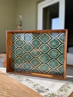 a wooden tray with blue and green designs on it sitting on top of a table