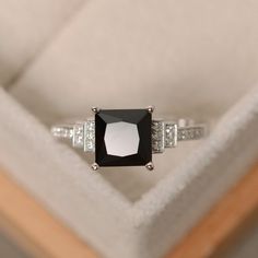 a black and white diamond ring sitting on top of a cushioned surface in a box