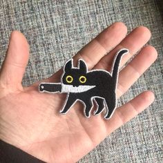 a hand holding a small black and white cat brooch on it's palm