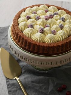 a cake with white frosting and red berries is on a plate next to a fork