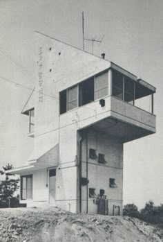 an old black and white photo of a building on top of a hill with windows