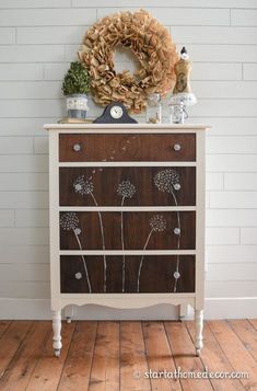 an old dresser has dandelions painted on the front and sides with white paint