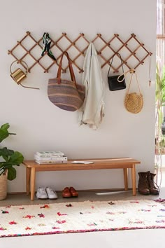 a wooden bench sitting next to a wall with purses and handbags hanging on it