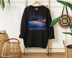 Get ready to ride the waves of style with our Malibu California sweatshirt! This amazing design features a captivating 3D-like graphic of Surfrider Beach at night, capturing the allure of this iconic surf spot. The word "Malibu" is elegantly written above in a playful and elegant script font, while "California" boldly stands below in a bold and stylish san-serif font, both in the same eye-catching color. Whether you're a beach lover, a surf enthusiast, or simply captivated by the coastal charm of Malibu, this sweatshirt is a must-have addition to your wardrobe. So, catch the cool California vibes and rock this stylish and cozy sweatshirt wherever your Malibu adventures take you! Designed with a perfect blend of soft cotton and breathable material, this classic heavy-blend crewneck sweatshi Relaxed Fit Sweatshirt For Beach Season Streetwear, Casual Sweatshirt With Front Print And Relaxed Fit, Beach Season Streetwear Sweatshirt Crew Neck, Cotton Graphic Print Sweatshirt For Surfing, Casual Graphic Print Sweatshirt For Surfing, Casual Streetwear Sweatshirt For Beach Season, Long Sleeve Tops For Beach Season Streetwear, Casual Crew Neck Sweatshirt For Surfing, Casual Cotton Sweatshirt For Surfing