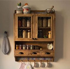 a wooden cabinet with pots and pans hanging from it's sides on a wall