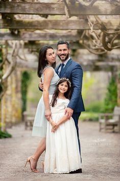 a couple and their daughter posing for a photo in front of an archway at the park