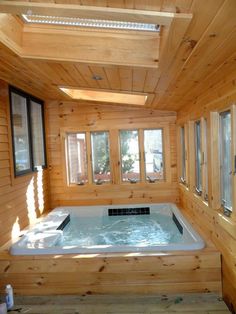 an indoor hot tub in the middle of a room with wood paneling and windows