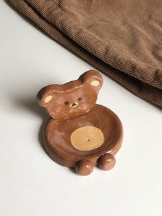 a brown teddy bear sitting on top of a white table next to a brown bag