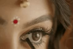 a woman's eye with red and white dots on her forehead is reflected in the mirror