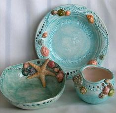 three ceramic dishes with seashells and starfish on them, one is blue