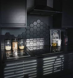 a kitchen with black cabinets and glass jars on the stove top, next to an oven