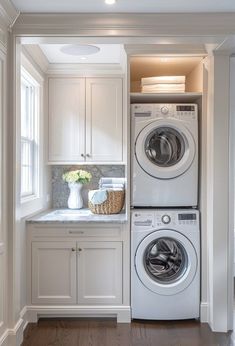 a washer and dryer in a white laundry room with wood flooring on the side