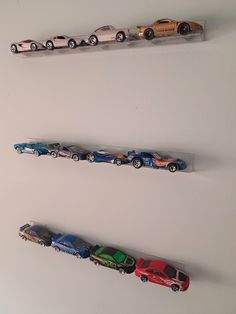 three toy cars are lined up on the wall next to each other in different colors