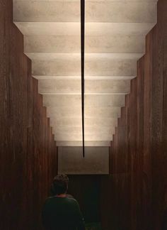 a person walking down a long hallway with a cross hanging from the ceiling above them