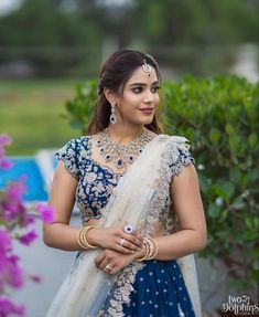 a woman in a blue and white lehenga with gold jewelry on her neck